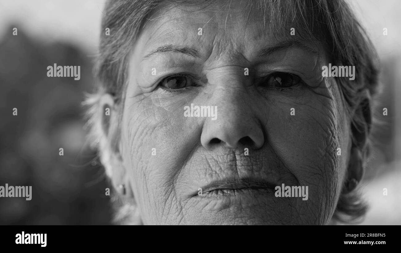 Resolute Senior Woman Portrait in dramatischem Schwarz-Weiß. Nahaufnahme des Gesichts, das auf die Kamera blickt. Ältere Frau mit Falten und entschlossenem Ausdruck in Stockfoto