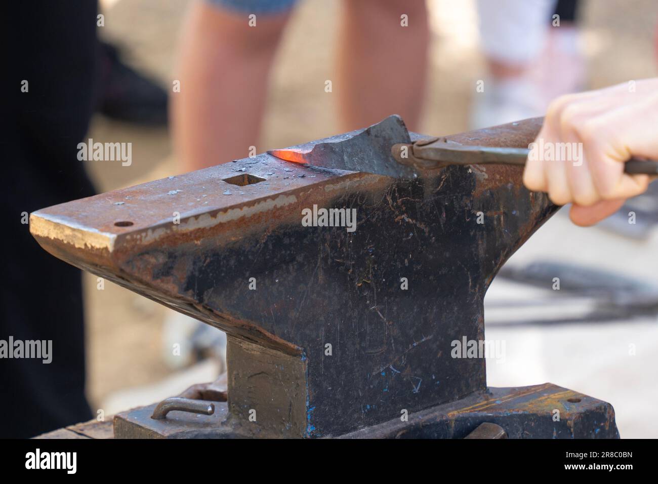 Eine Hand, die ein glühendes Eisen auf einen Amboss hält Stockfoto