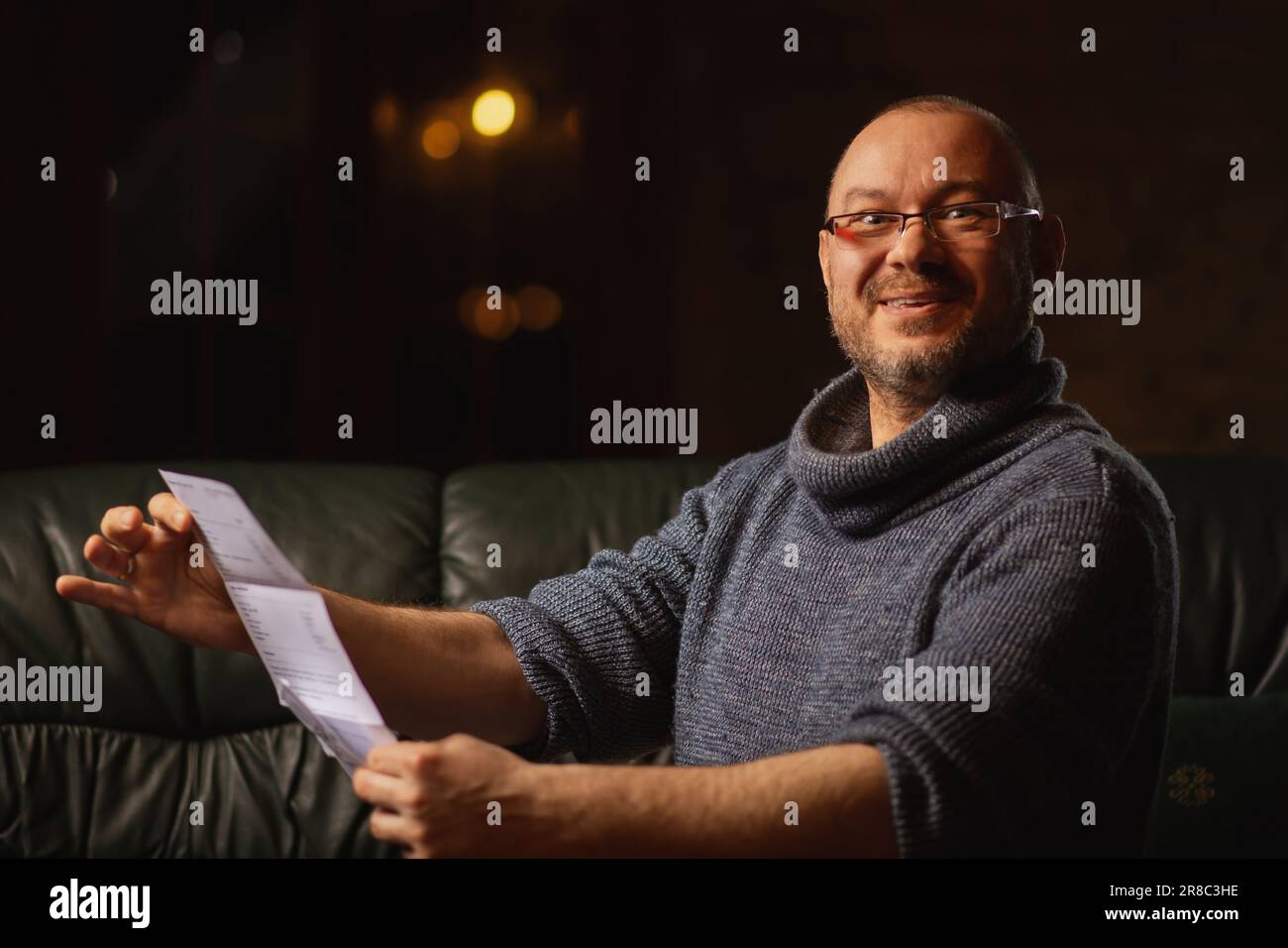 Fröhlicher Brief eines Mannes mittleren Alters mit Brille in seinen Händen. Gute Nachrichten, frohe Ereignisse. Stockfoto