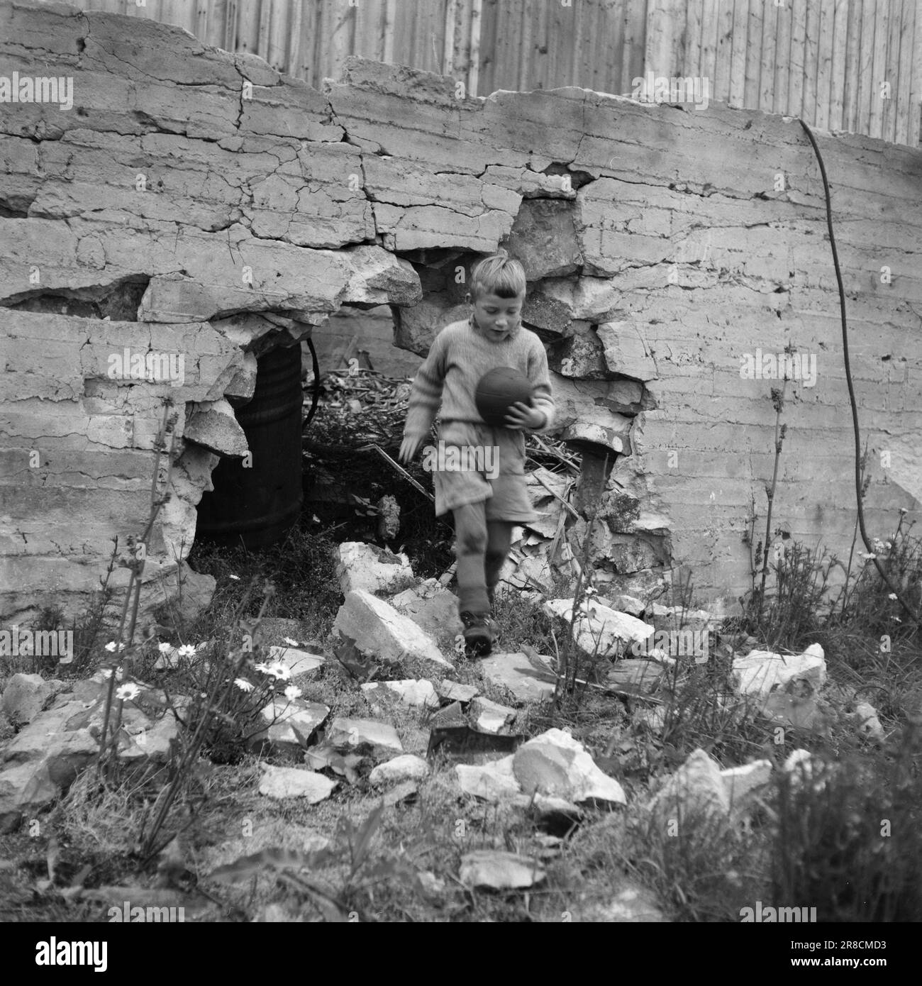 Tatsächlich 20-3-1947: Honningsvåg'Zwischen Baracken und Bergen am Meer...' Als die deutschen „Entstörungsabteilungen“ Honningsvåg verließen, blieb nur die winzige Holzkirche erhalten und bezeugte, dass Honningsvåg eine florierende kleine Gemeinde war, das größte Fischerdorf von West Finnmark. Wie sieht es heute in Honningsvåg aus, fast drei Jahre nachdem die Deutschen in Finnmark ihre Verwüstung begannen? Wie läuft es eigentlich mit der umstrittenen Restaurierung im Norden? Wesle Svend Helge Hansen springt aus einem Loch in der Fundamentwand, auf der sein Zuhause einst stand. Svend Helge ist nicht wieder da Stockfoto