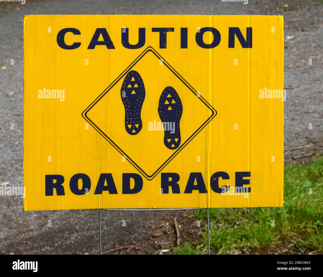 Ein Schild entlang einer Straße warnt Autofahrer, die Teilnehmer des Straßenrennens auf der Straße zu kennen. Stockfoto