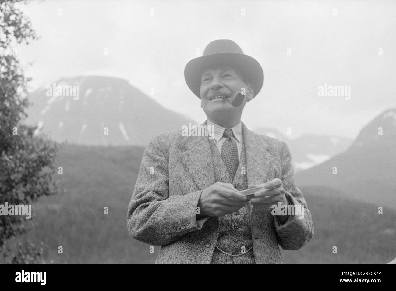 Derzeit 17-1951: Attlee und seine Ehefrau auf dem Dach des norwaybritischen Premierministers Clement Attlee waren in Norwegen im Urlaub. Mrs. Attlee hat schon früher Schneebälle geworfen - in ihrer Kindheit war sie an vielen Schneeballkämpfen auf Hampstead Heath beteiligt, sagte sie. Auf der Reise nach Juvasshytta wanderte sie definitiv zum Gletscher, um wieder Schnee in ihren Händen zu spüren, und sie schleppte ihren Mann mit sich. Sie forderte ihn auch zu einem kleinen Duell mit dieser kalten Munition heraus, aber er lehnte es entschieden ab. Er blieb in sicherer Entfernung außerhalb der Reichweite, zog seinen geliebten Schnupftabak raus, dass er eigentlich nur A rauchen darf Stockfoto