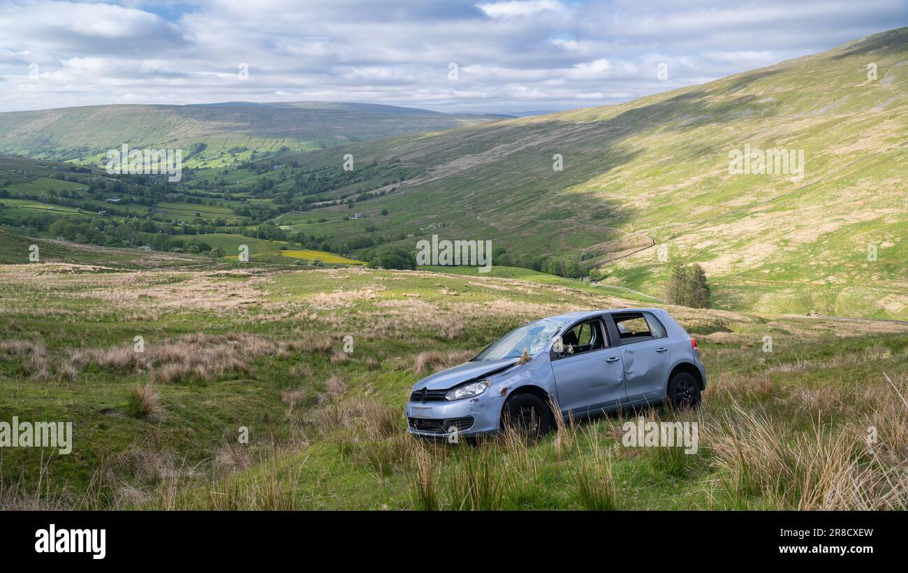 Ein Auto wurde auf einer steilen Bergweide zerstört, nachdem er von einer engen Landstraße in Dentdale, Cumbria, Großbritannien, abgekommen war. Stockfoto