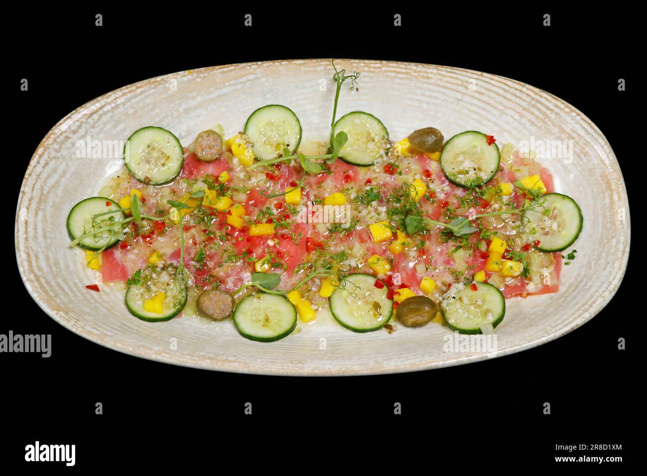 Marinierter Gelbflossenthun Crudo, ähnlich Ceviche und Tartare mit Zitrone, Gurke, Chili, Mango und Kräutern Stockfoto