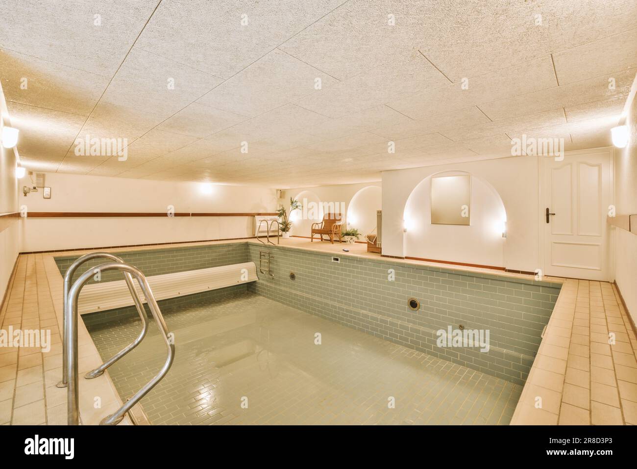 Ein Whirlpool im Innenbereich in der Mitte eines Zimmers mit gefliestem Boden und weiß bemalten Wänden Stockfoto