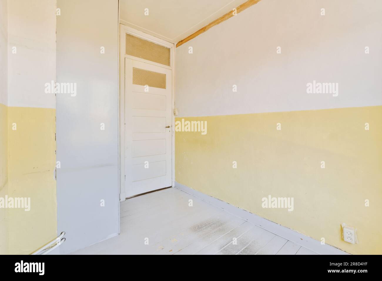 Ein leerer Raum mit gelber Farbe an den Wänden und einer weißen Tür auf der linken Seite wird nicht benutzt, aber Stockfoto