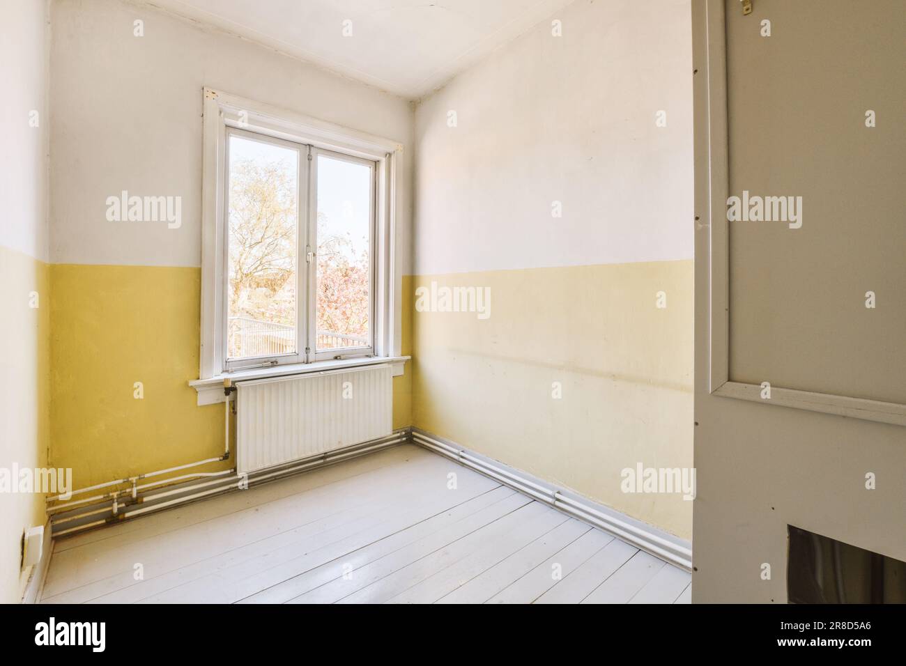 Ein leerer Raum mit gelber Farbe an den Wänden und weißem Holzfußboden vor einem offenen Fenster Stockfoto