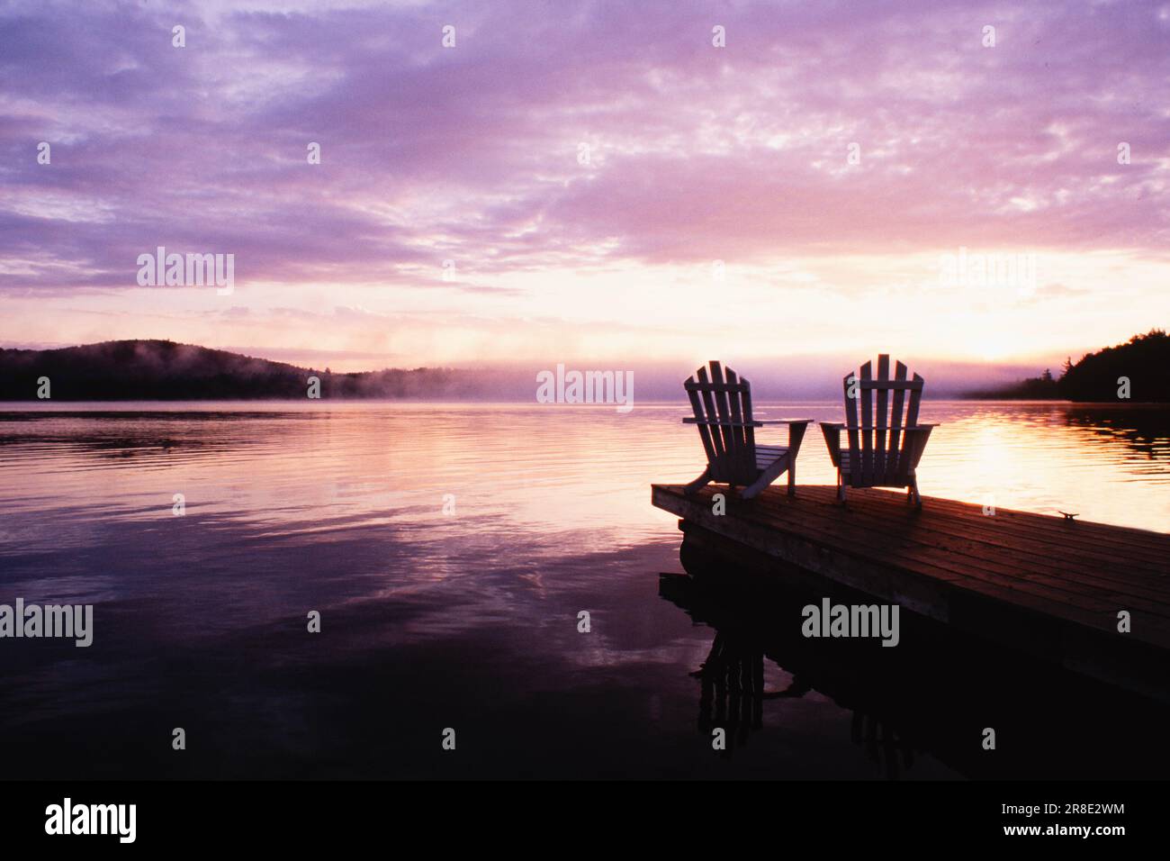 USA, New York State, Saranac Lake, Silhouettes of adirondack Stühle am Pier am Lake Placid bei Sonnenaufgang im Adirondack Park Stockfoto