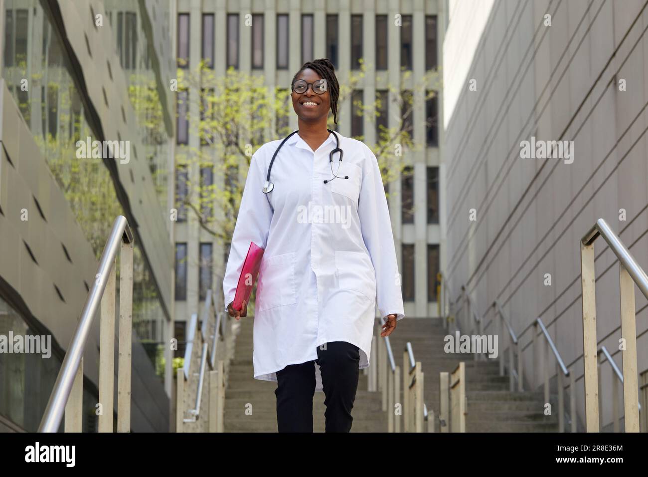 Porträt einer lächelnden Ärztin auf den Stufen in der Stadt Stockfoto