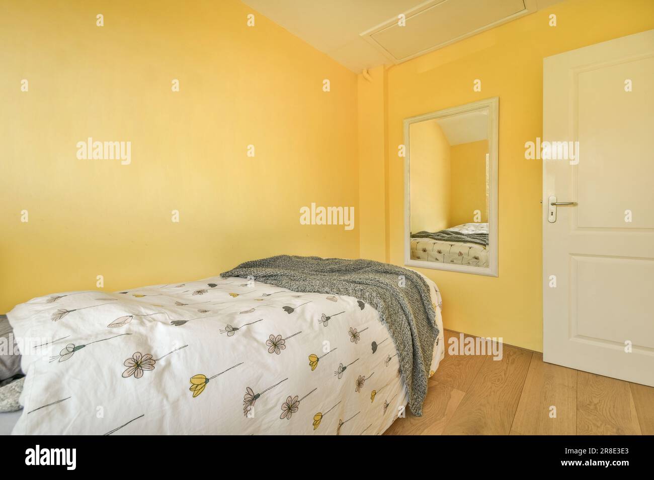 Ein Schlafzimmer mit gelben Wänden und Holzfußboden im Vorderbereich - Bild ist von einem anderen Zimmer auf der rechten Seite Stockfoto