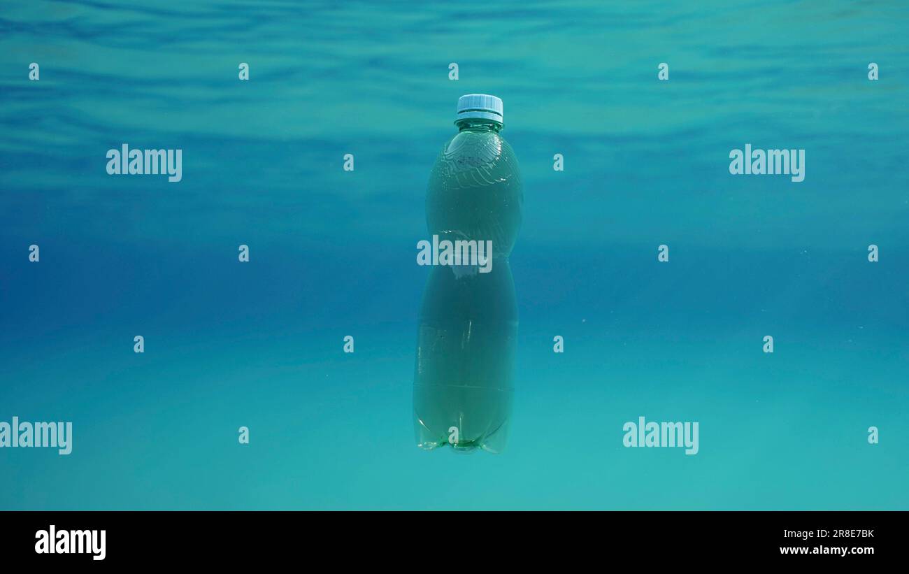 Grüne Plastikflasche treibt unter blauem Wasser. Plastikverschmutzung des Ozeans, weggeworfene Plastikflasche schwimmt unter Wasser im Sonnenlicht, Rotes Meer Stockfoto