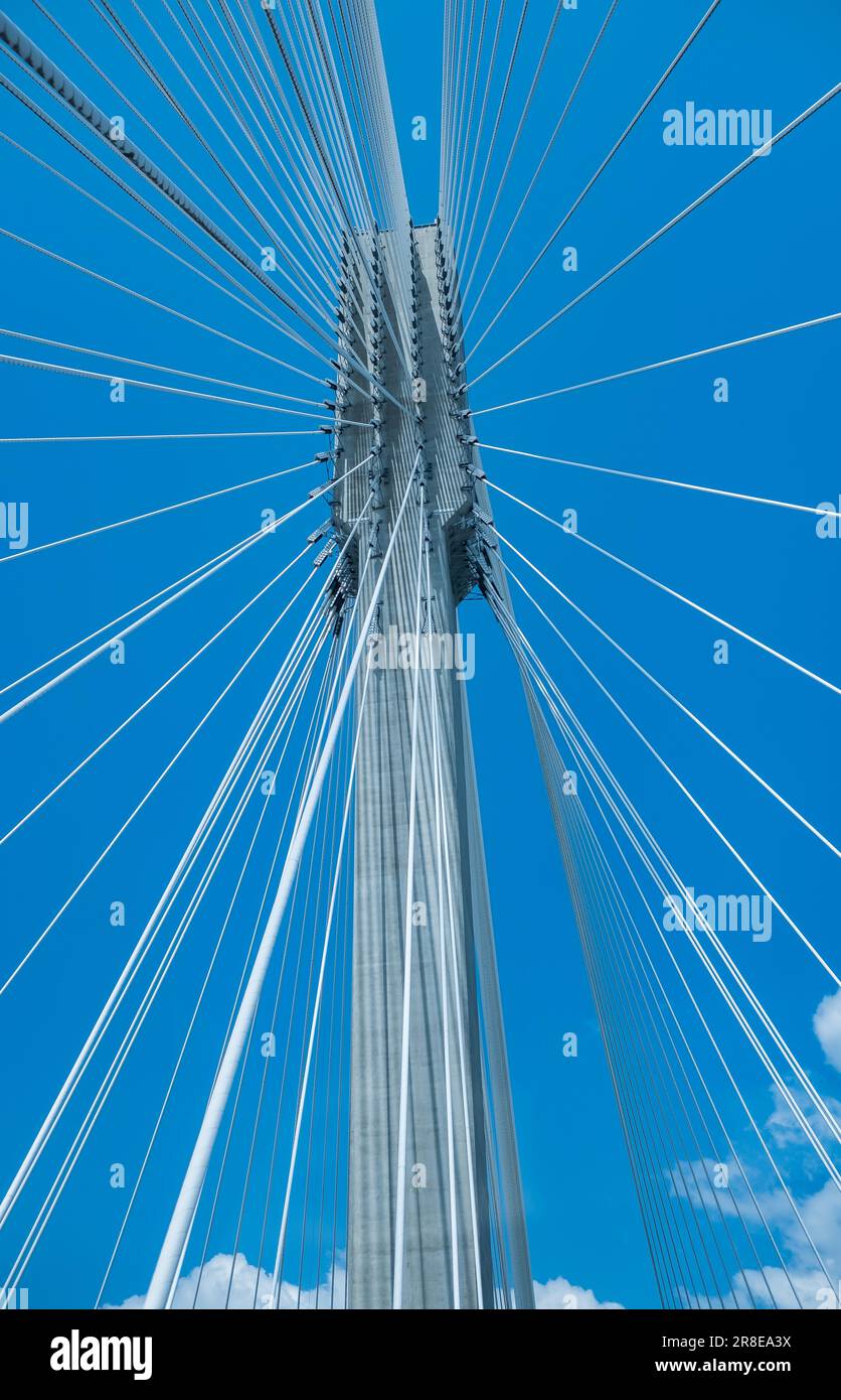 Moderner Brückenpylon vor blauem Himmel. Detail der mehrspaltigen Kabelbrücke. Lineare perspektivische Ansicht einer weissen Kabelaufhängung Alex Stockfoto