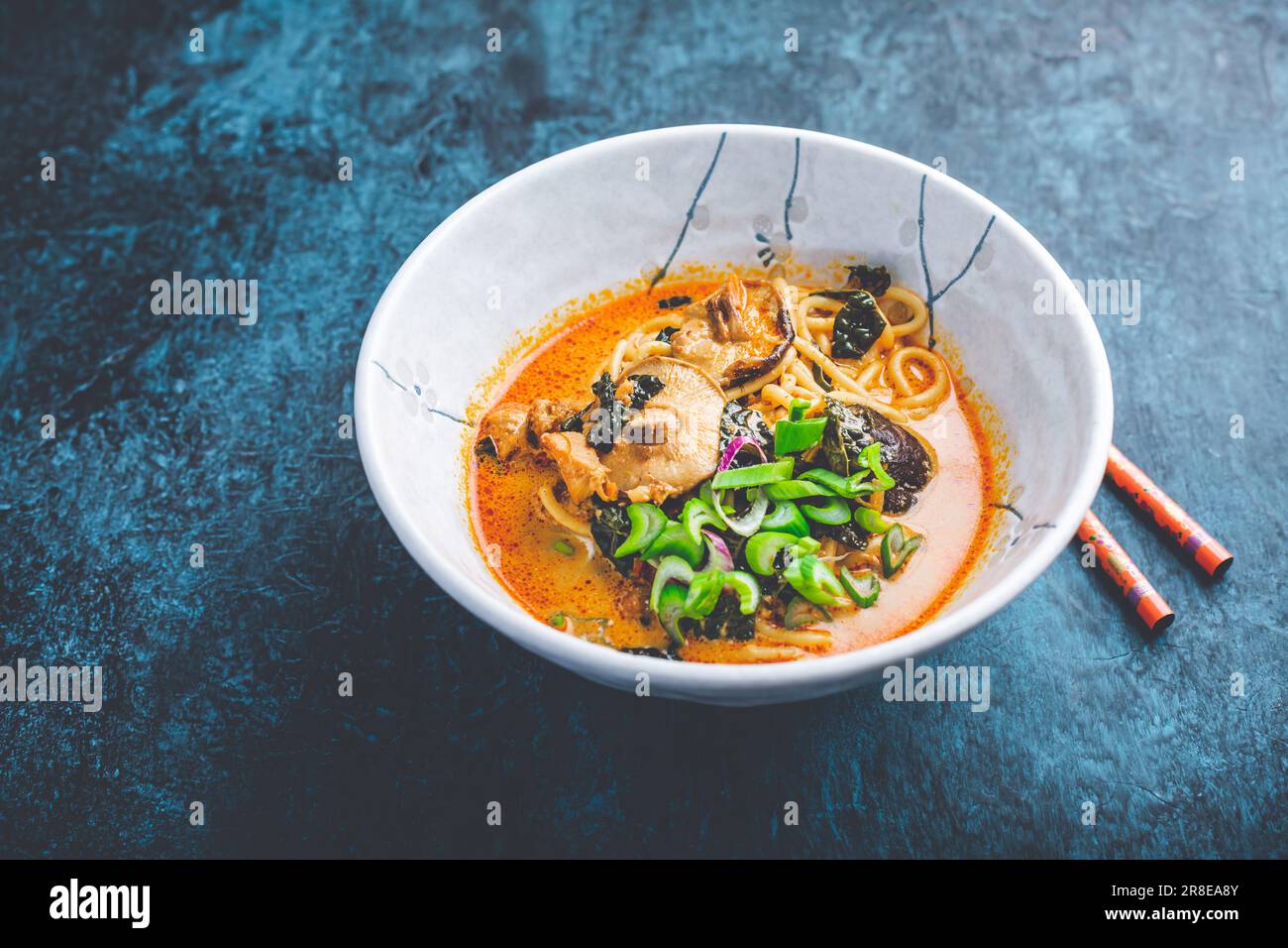 Thailändische rote Currysuppe mit Huhn, Shiitake-Pilzen, Kokosmilch und grünen Zwiebeln Stockfoto