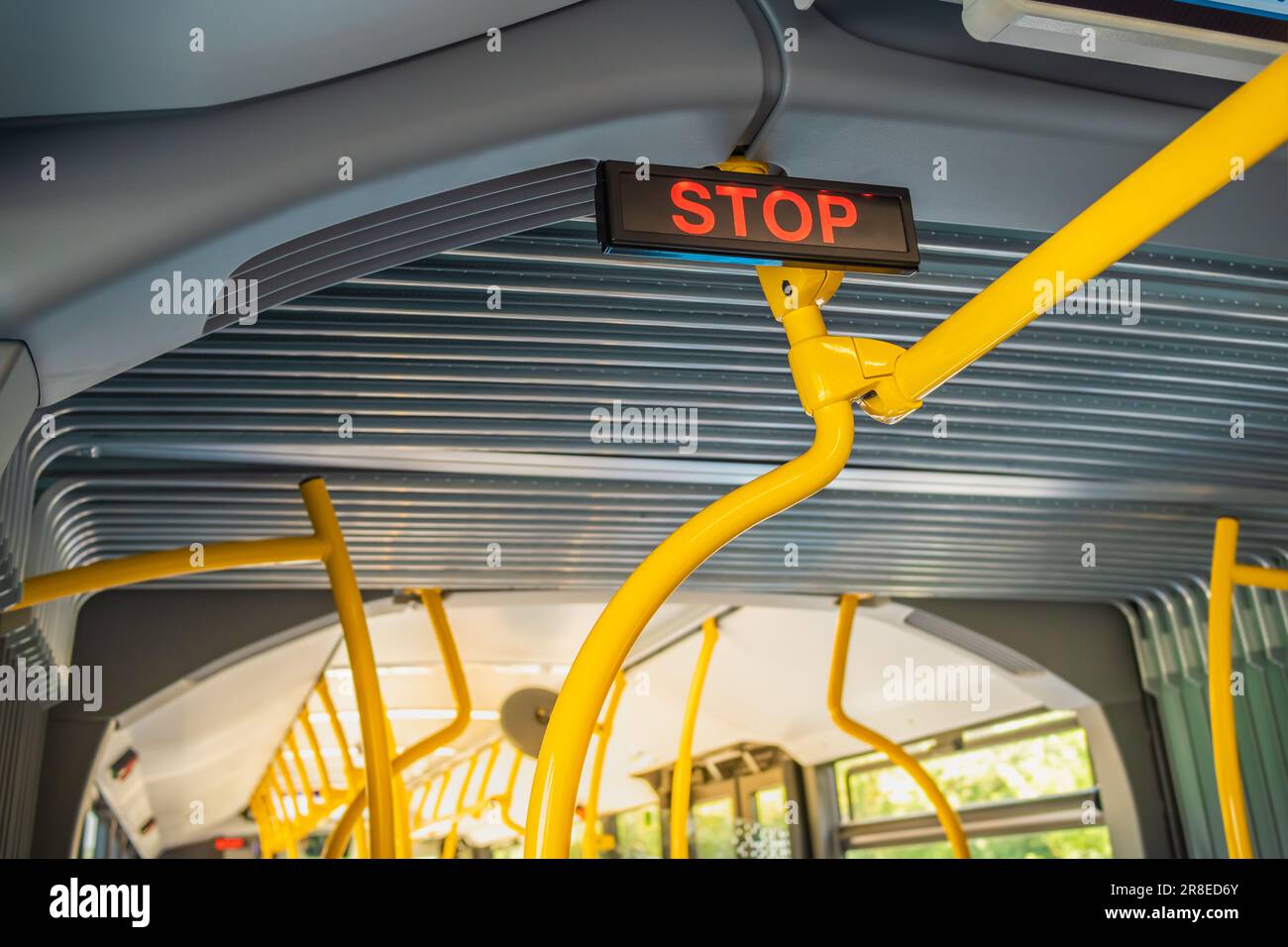 Stoppschild im Stadtbus. Leere Bushaltestelle. Bus mit blauen Sitzen und gelben Handläufen Stockfoto