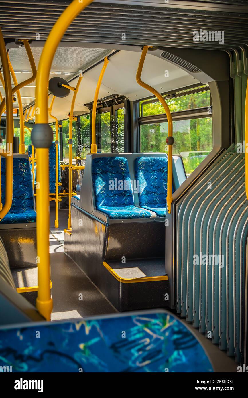 In einem Stadtbus. Leere Bushaltestelle. Bus mit blauen Sitzen und gelben Handläufen. Öffentlicher Nahverkehr. Stockfoto