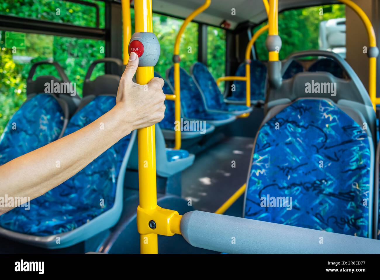 In einem Stadtbus. Leere Bushaltestelle. Bus mit blauen Sitzen und gelben Handläufen. Öffentlicher Nahverkehr. Stockfoto