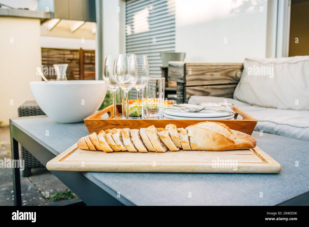 Frisch gebackenes Baguette mit gesundem Snack und Gläsern auf der Terrasse oder Terrasse Stockfoto