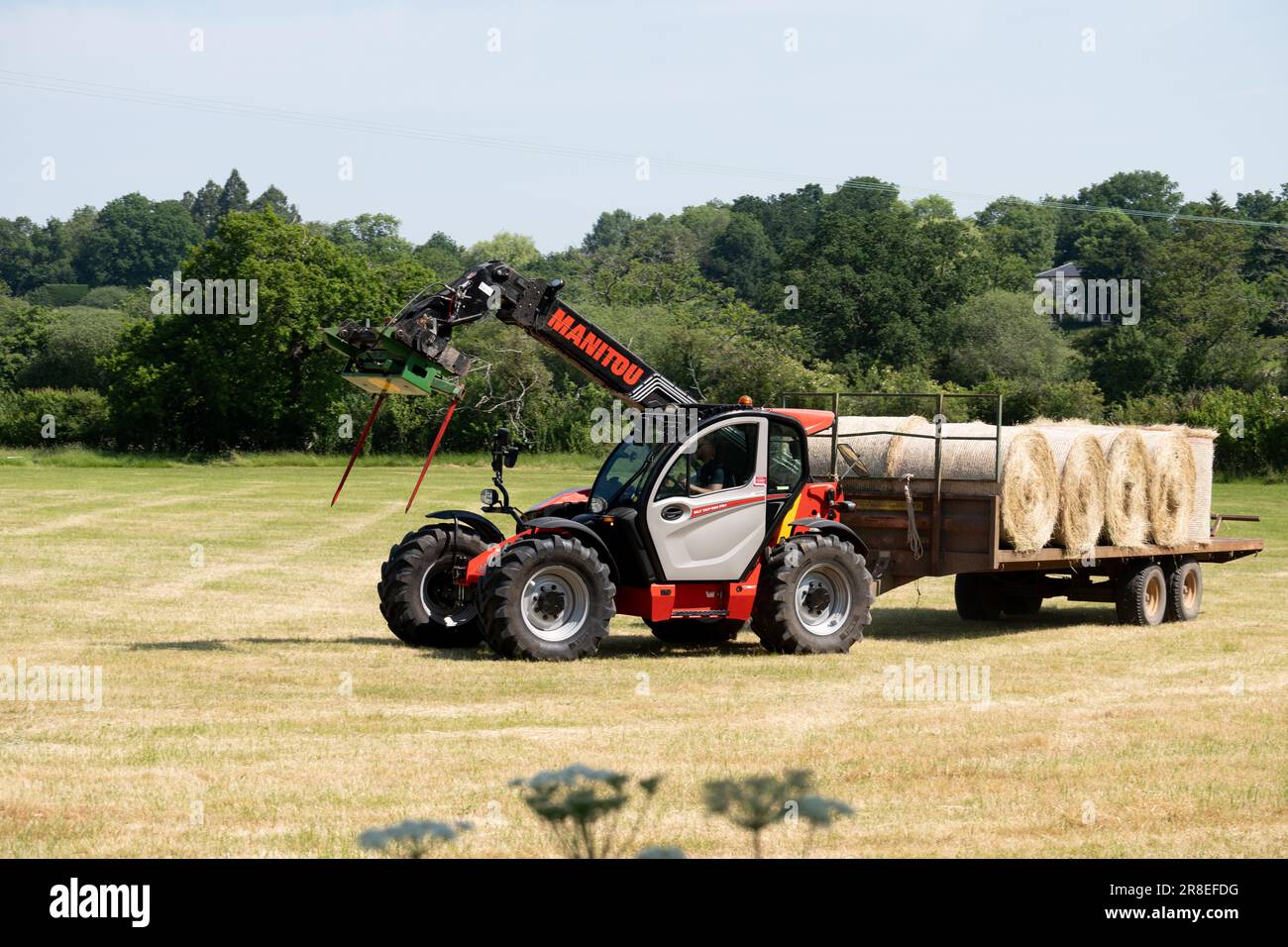 Traktor von Manitou, der einen Anhänger mit Heuballen zieht, Warwickshire, Großbritannien Stockfoto