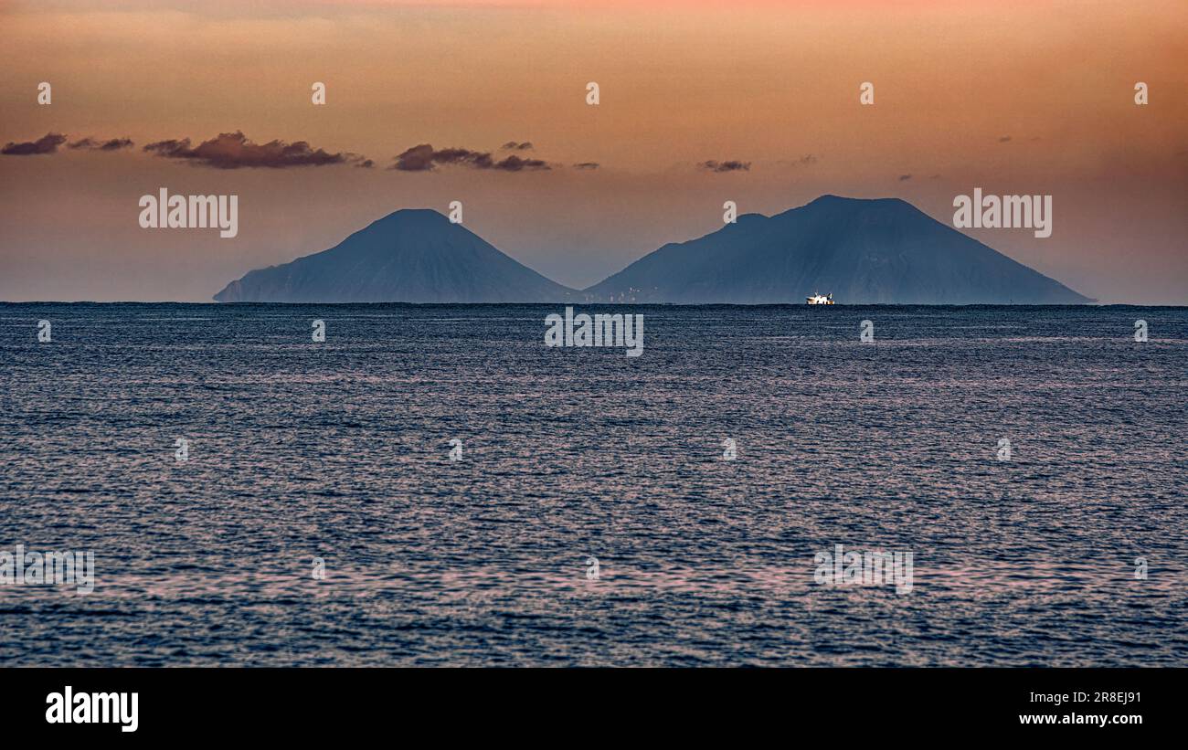 Silhouette der Äolischen Inseln im warmen und farbenfrohen Licht des Sonnenuntergangs im Winter. Sizilien, Italien, Europa Stockfoto
