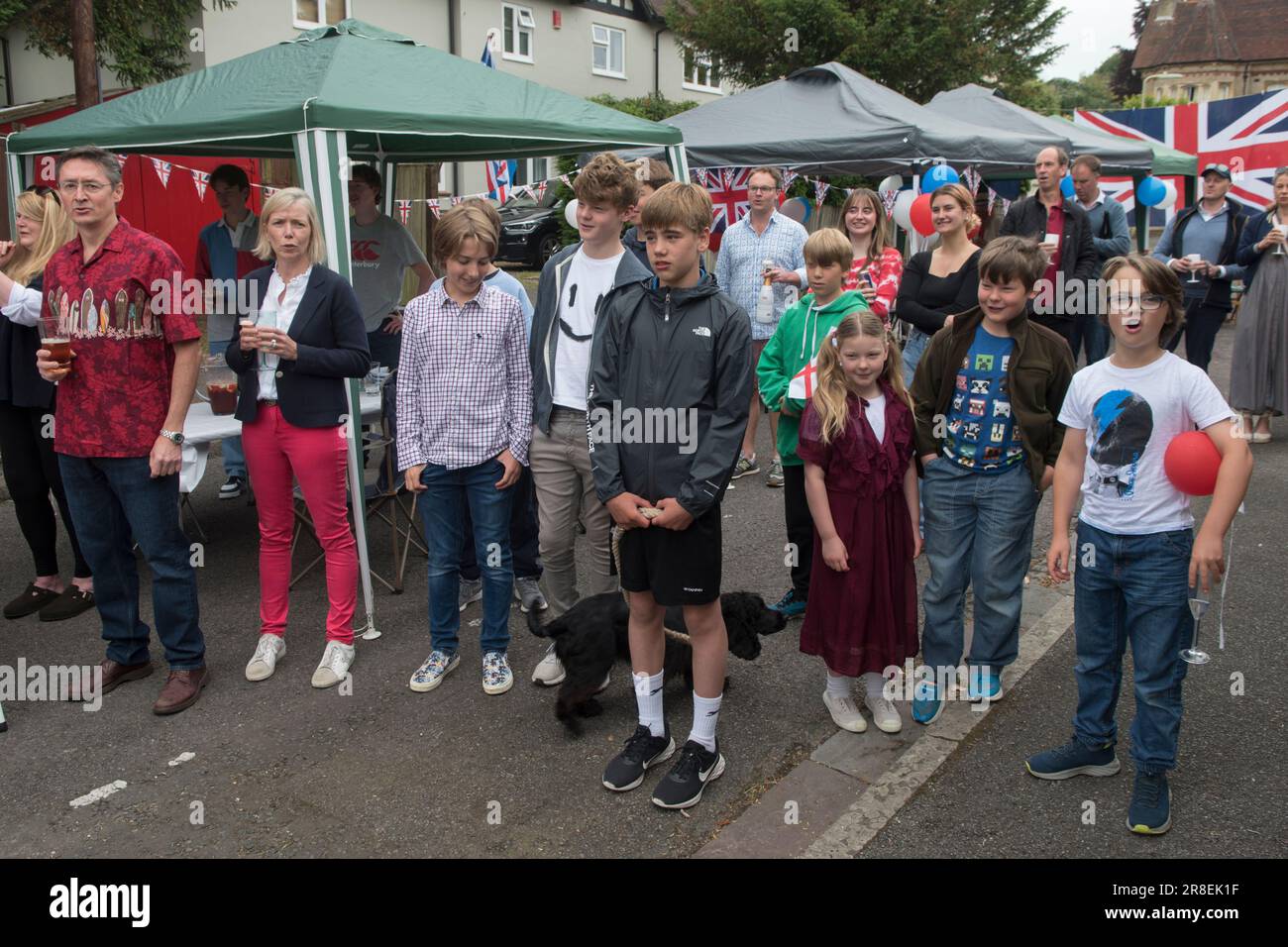 Singen Sie die Nationalhymne, Gott rette die Königin. Kinder kennen die Worte nicht. Winchester, Hampshire, England, 5. Juni 2022. Queen Elizabeth II. Platinum Jubilee Straßenfest in der Grafton Road. Die Straße war geschlossen, mit Fähnchen dekoriert. Die Anwohner wurden ermutigt, rot, weiß und blau zu tragen. Um 12 Uhr gab es einen lokalen Toast und drei Anfeuerungen für die Königin und dann das Singen der Nationalhymne. HOMER SYKES AUS DEN 2020ER JAHREN Stockfoto Singen Sie die Nationalhymne, Gott rette die Königin. Kinder kennen die Worte nicht. Winchester, Hampshire, England, 5. Juni 2022. Queen Elizabeth II. Platinum Jubilee Straßenfest in der Grafton Road. Die Straße war geschlossen, mit Fähnchen dekoriert. Die Anwohner wurden ermutigt, rot, weiß und blau zu tragen. Um 12 Uhr gab es einen lokalen Toast und drei Anfeuerungen für die Königin und dann das Singen der Nationalhymne. HOMER SYKES AUS DEN 2020ER JAHREN Stockfoto