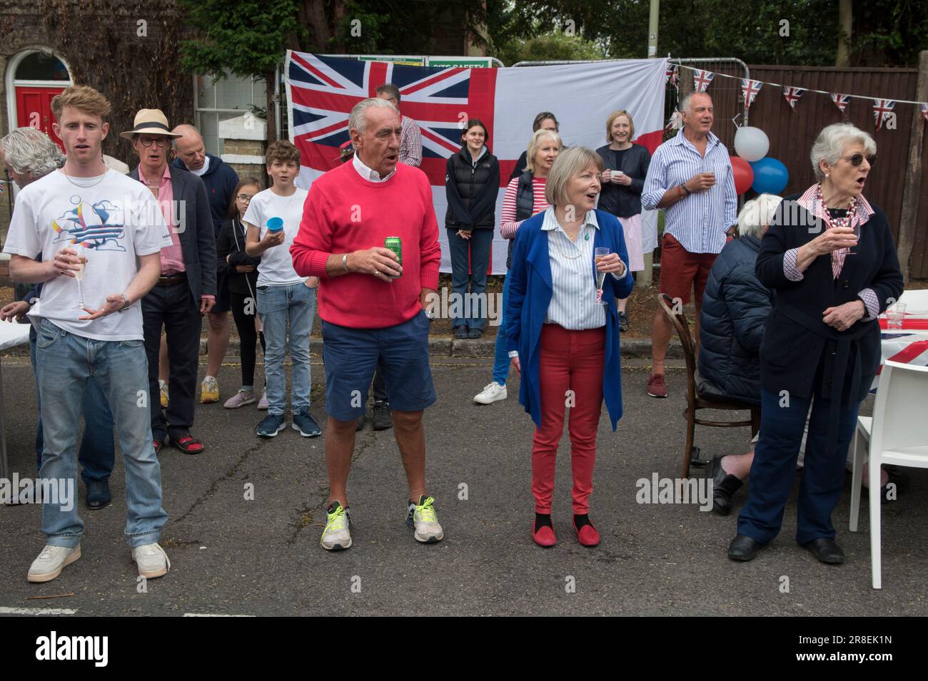 Nachbarn singen die Nationalhymne, Gott rette die Königin. Winchester, Hampshire, England, 5. Juni 2022. Queen Elizabeth II. Platinum Jubilee Straßenfest in der Grafton Road. Die Straße war geschlossen, mit Fähnchen dekoriert. Die Bewohner der Nachbarschaft wurden dazu ermutigt, rot, weiß und blau zu tragen. Um 12 Uhr gab es einen lokalen Toast und drei Anfeuerungen für die Königin und dann das Singen der Nationalhymne. HOMER SYKES AUS DEN 2020ER JAHREN Stockfoto