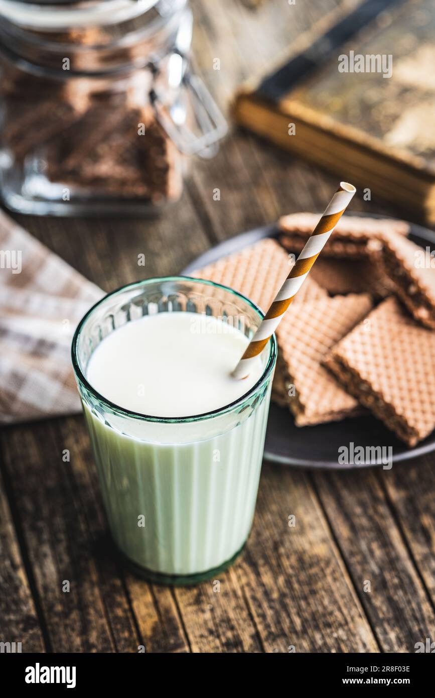 Ein Glas Milch mit gestreiftem Stroh auf dem Holztisch. Stockfoto