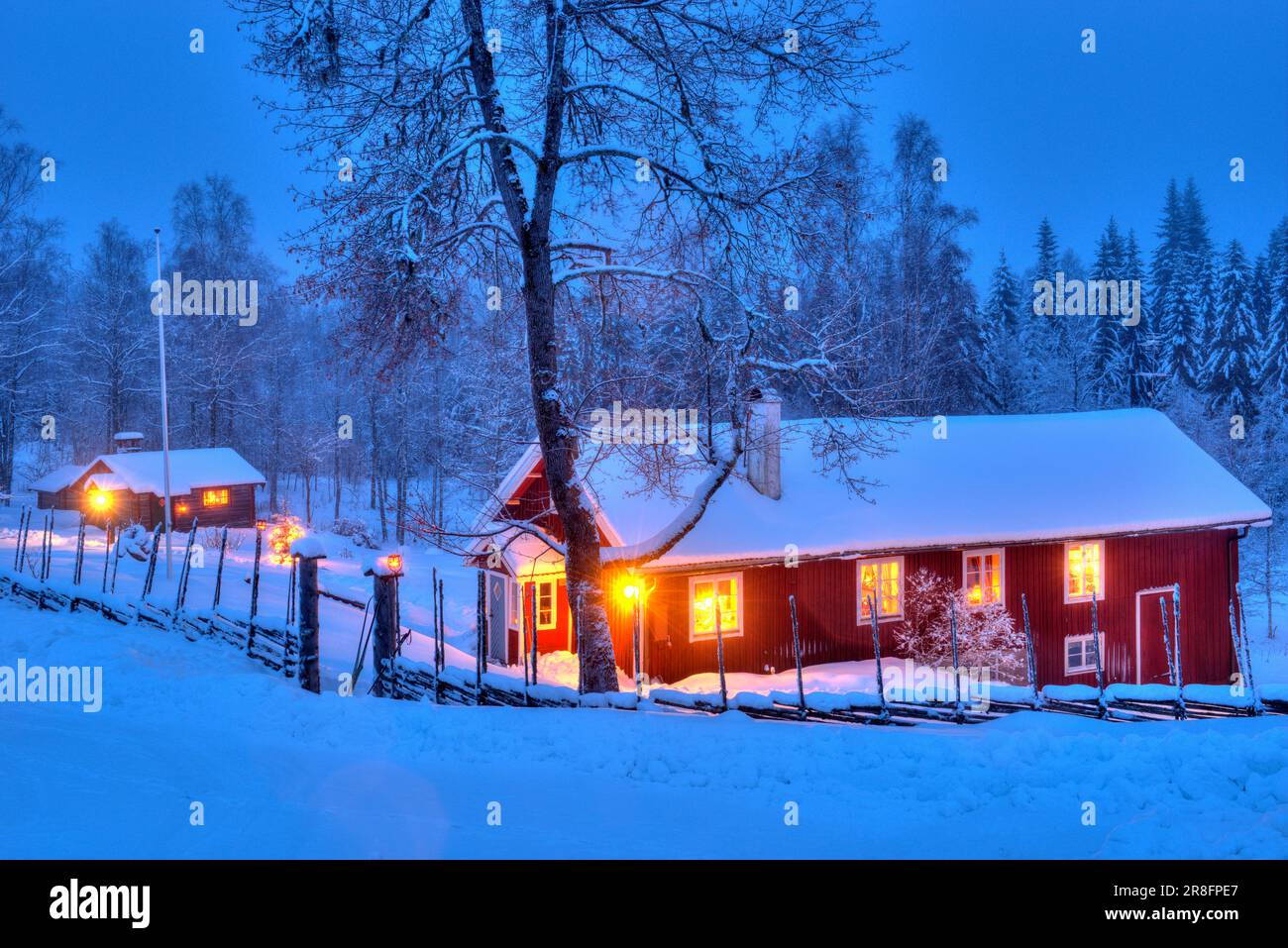 Ein falu rotes Haus mit Lichtern in den Fenstern in einer Winternacht Stockfoto