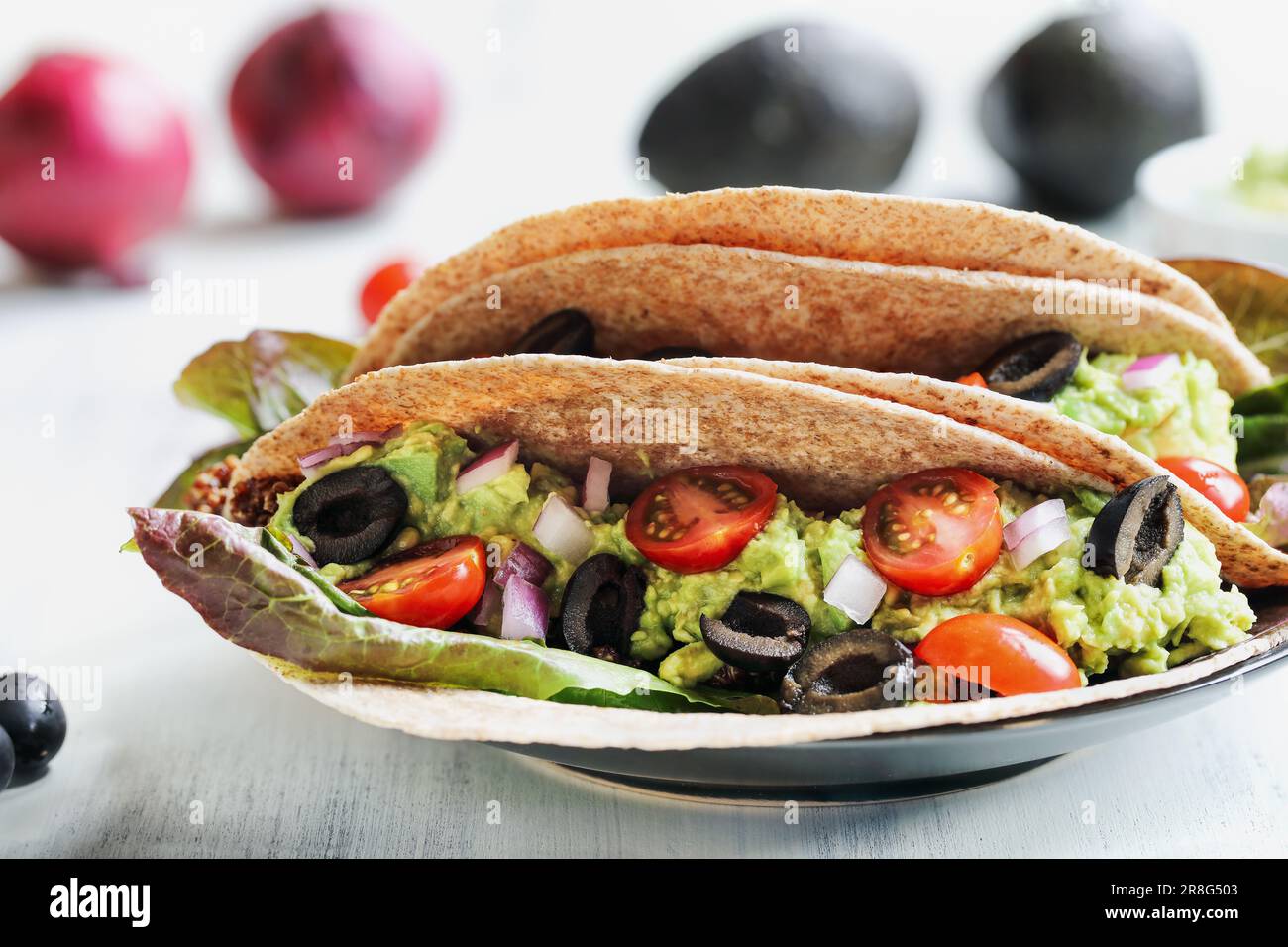 Ein gesundes Mittag- oder Abendessen mit veganischem/vegetarischem Taco-Wrap aus roter Quinoa mit Taco-Saison, Römersalat, Tomaten, Guacamole. Stockfoto