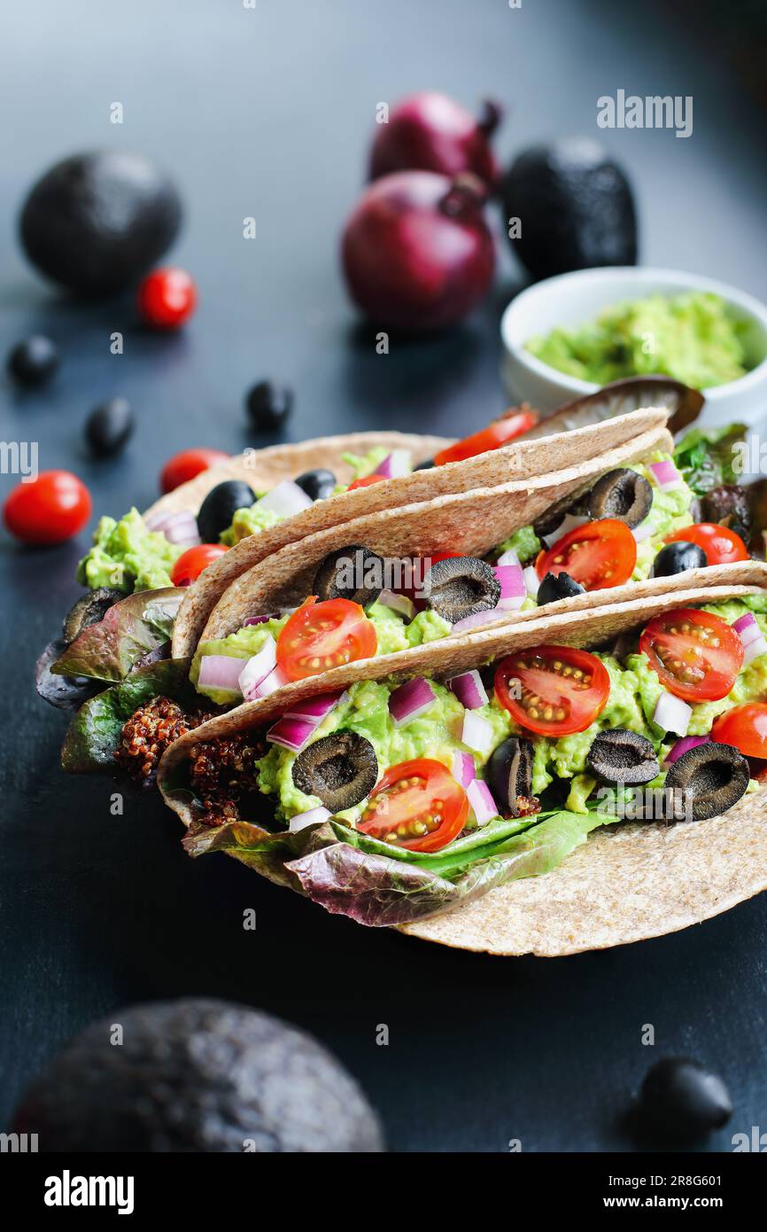 Ein gesundes Mittag- oder Abendessen mit veganischem/vegetarischem Taco-Wrap aus roter Quinoa mit Taco-Saison, Römersalat, Tomaten, Guacamole. Stockfoto