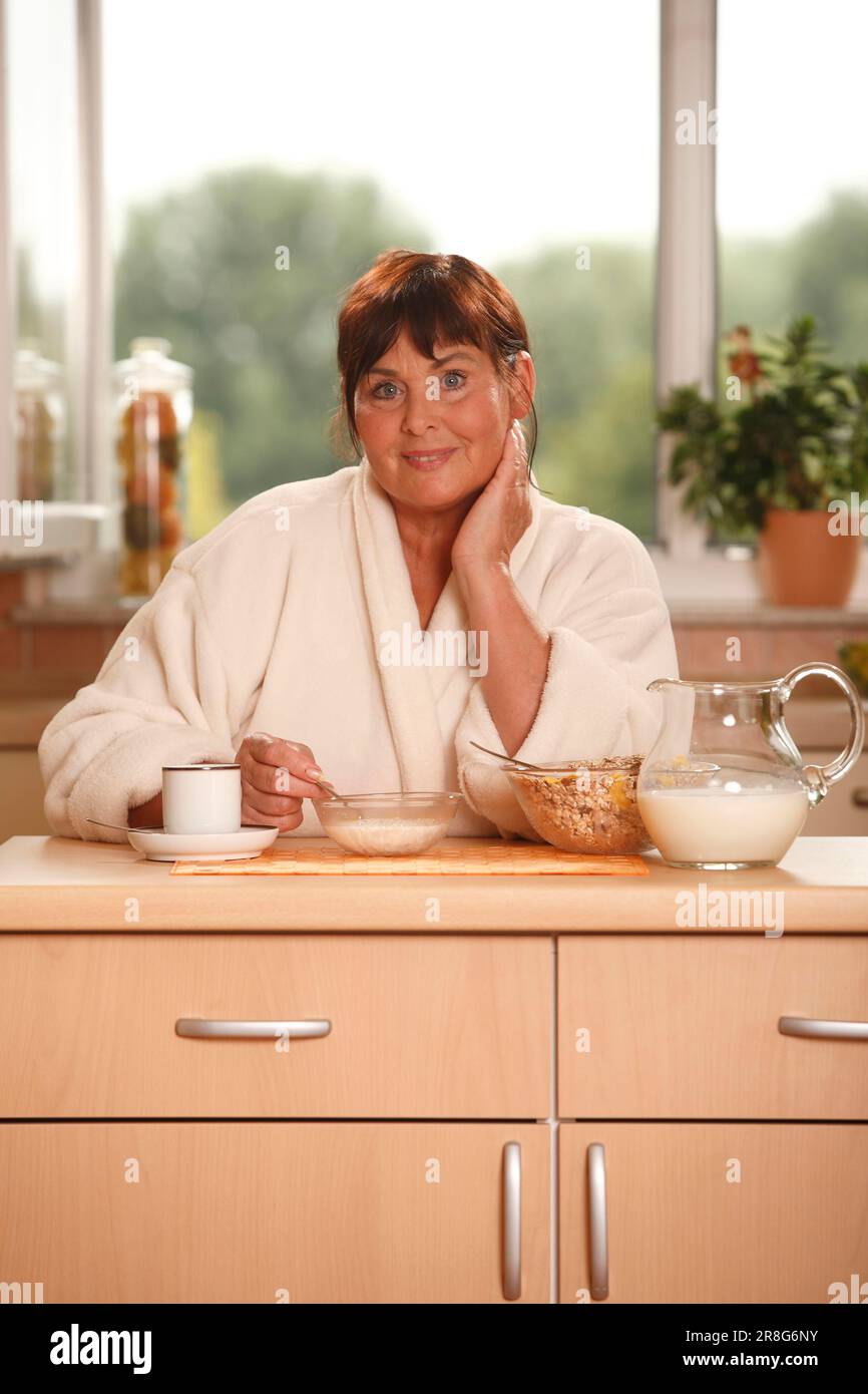 Frau beim Frühstück, Frühstück, Frühstück, Topf mit Milch, Schüsseln, Müsli, eine Tasse Kaffee, Frühstück Stockfoto