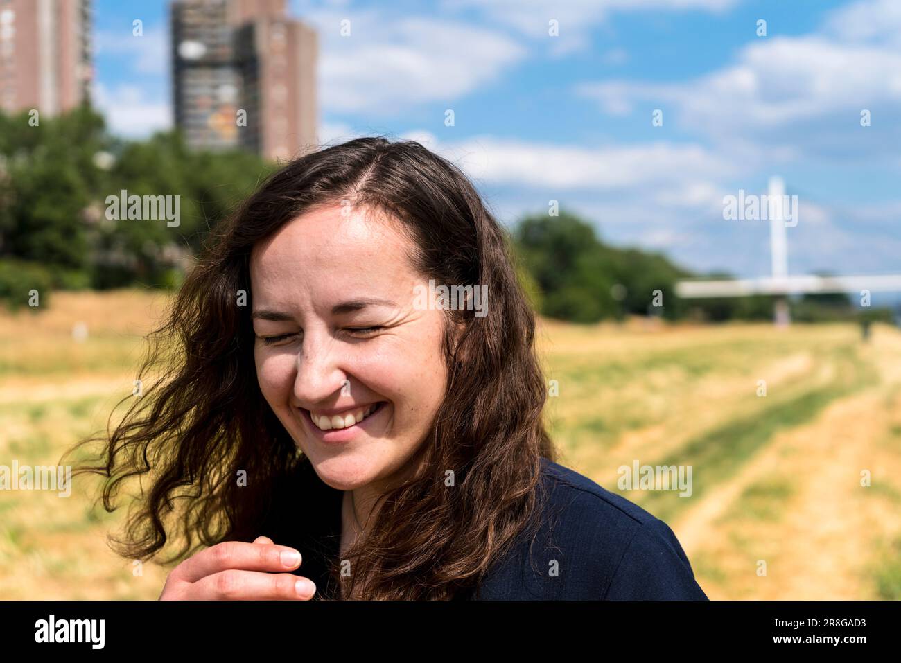 Junge Frau mit offenem Haar im städtischen Umfeld, lachend Stockfoto
