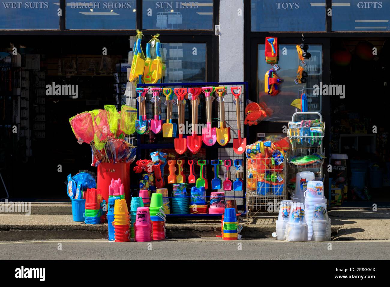 Ein Laden, der farbenfrohe Strandartikel verkauft - Eimer, Pik, Bälle usw. im Lyme Regis an der Jurassic Coast, Dorset, England, Großbritannien Stockfoto