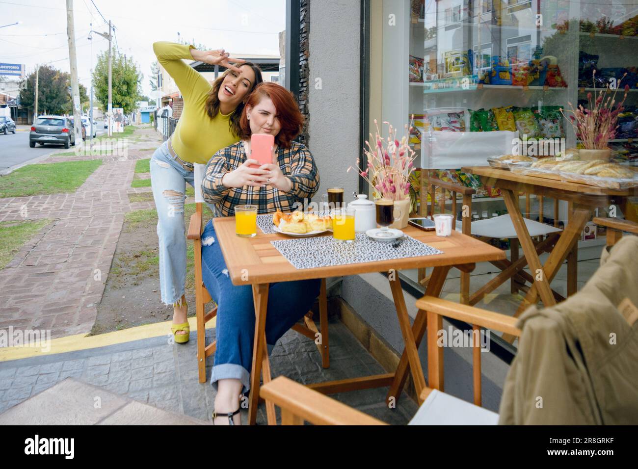 Zwei junge lateinische Frauen argentinischer ethnischer Herkunft, die ein Selfie-Foto mit dem Telefon machen, bevor sie vor der Cafeteria frühstücken, People Concept, c Stockfoto