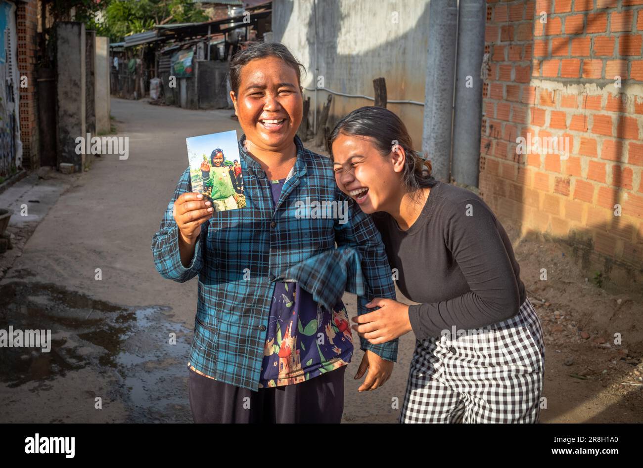 Eine Mutter einer ethnischen Minderheit von Bahnar hält ein Foto von sich selbst als 10-jähriges Mädchen, während ihre Tochter in Kontum, Vietnam, lacht. Die Bahnar sind eine von 54 et Stockfoto