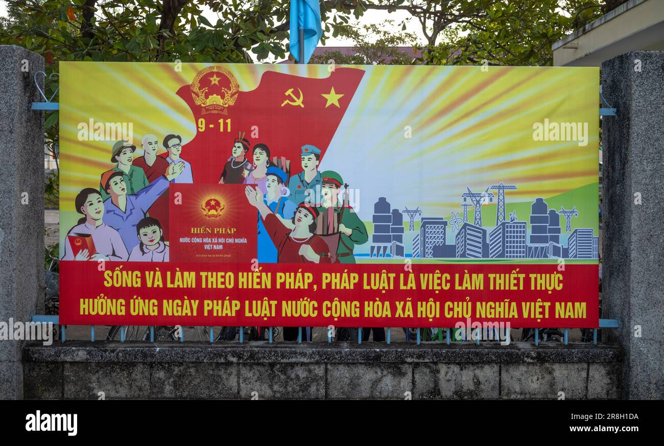 Ein gemaltes kommunistisches Propagandafilt, das an den Toren einer skandalösen Schule in Kontum, im zentralen Hochland Vietnams, angebracht ist und die Bürger drängt Stockfoto