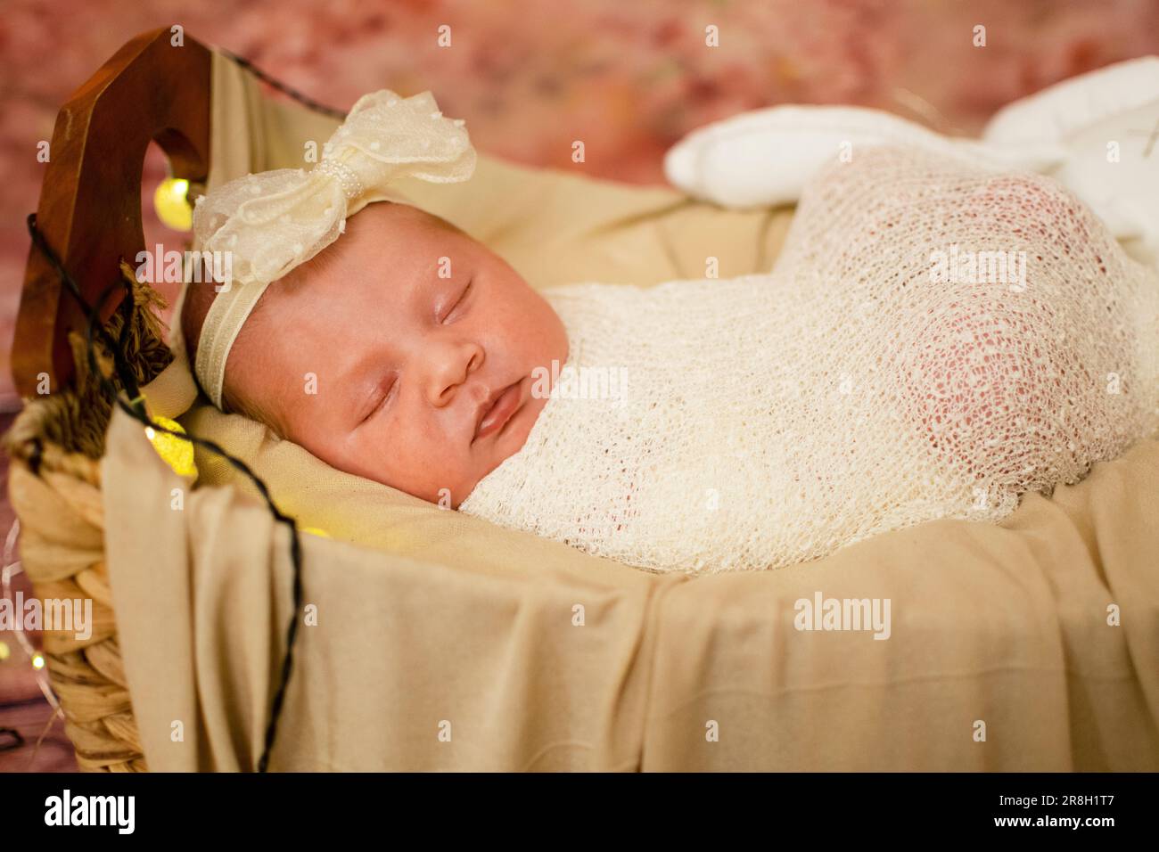Süßes, gesundes, kaukasisches, neugeborenes Baby Mädchen, das schläft, eingewickelt in eine Windel und Bogen. Stockfoto