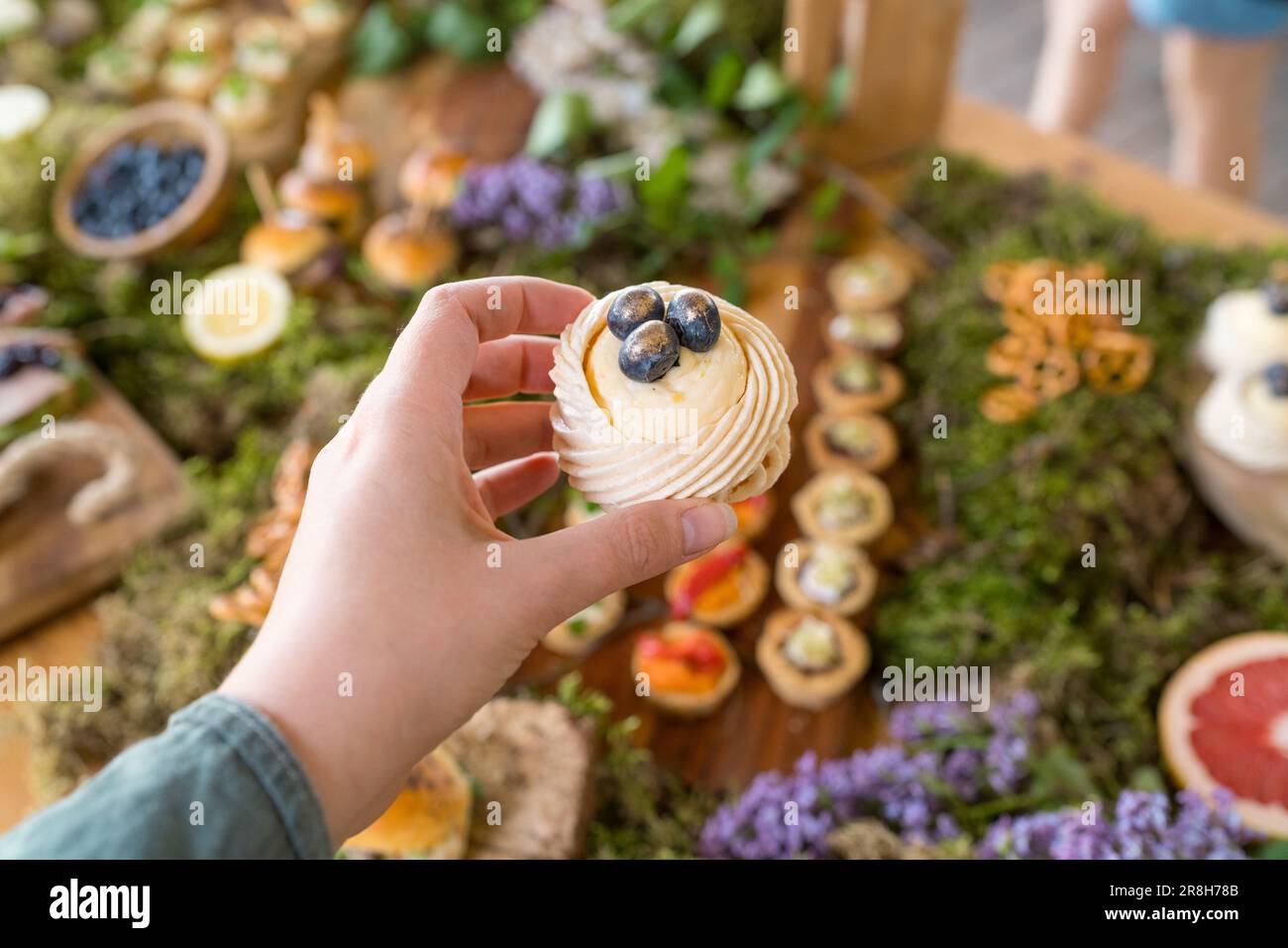 Weiblicher Gast auf einer rustikalen Party im Freien mit Mini-Pavlova-Dessert mit frischen Blaubeeren Stockfoto