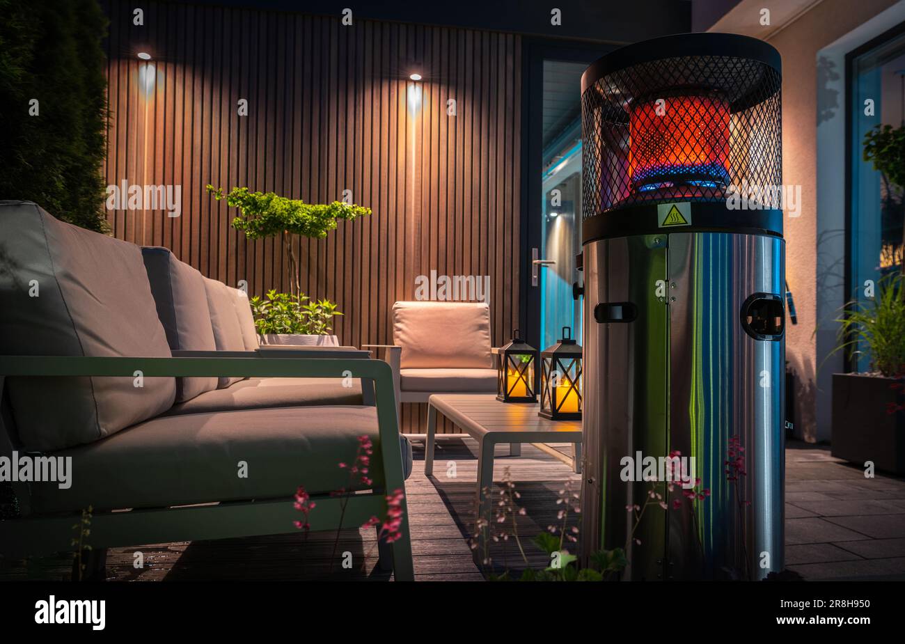 Moderne, gemütliche Terrasse mit Gasheizung, die den Bereich während des kalten Sommernachts wärmt. Hinterhof-Design Für Haushalte. Stockfoto