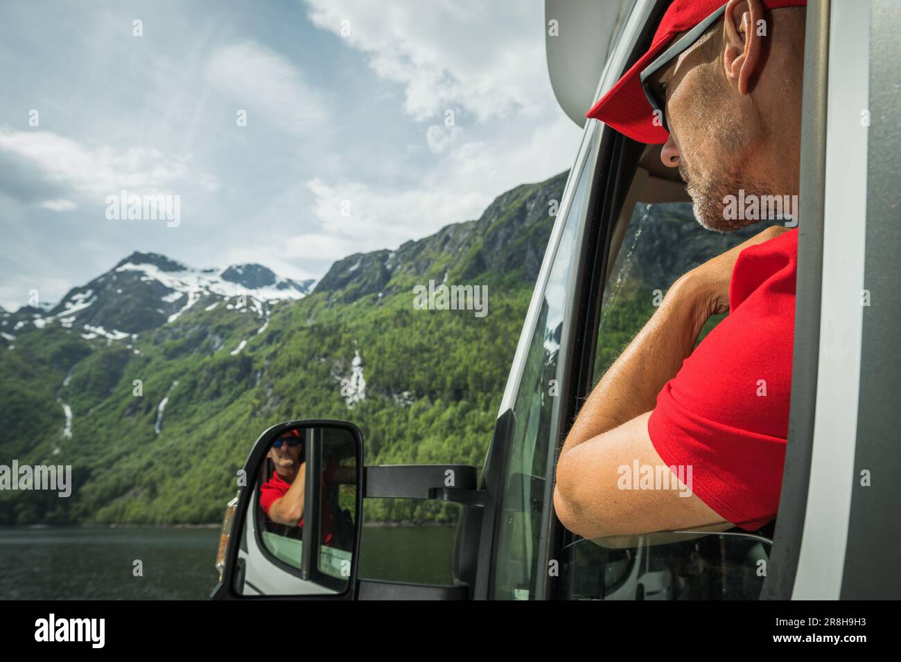 Weißer Tourist in seinen 40s Jahren, der vor seinem Wohnmobil-Fenster blickt und die Aussicht genießt. Malerische Norwegische Sommerlandschaft Stockfoto