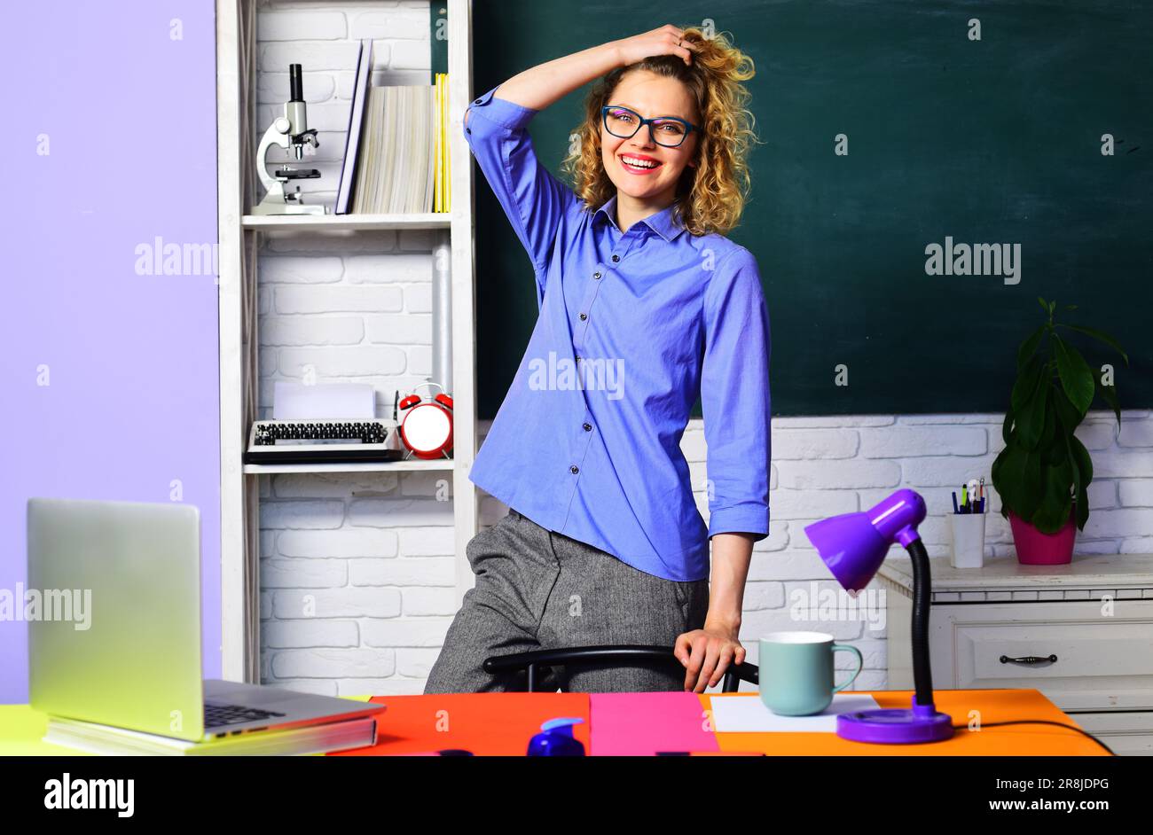 Zurück in die Schule. Positiver Brillenlehrer in der Schulklasse. Lernen, Bildung. Professioneller Lehrer oder Universitätsprofessor am Schreibtisch im Klassenzimmer Stockfoto