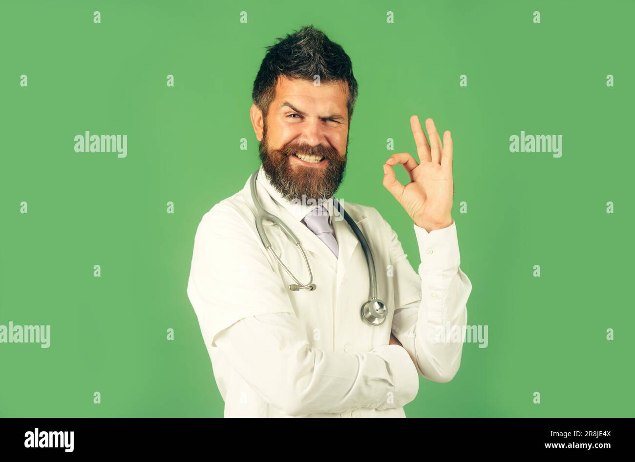 Glücklicher männlicher Arzt, der das Zeichen "OK" zeigt. Bärtiger Mann mit Stethoskop im Kittel mit Zeichen-in-Zulassung. Medizin, Klinik, Behandlung, Gesundheitswesen Stockfoto