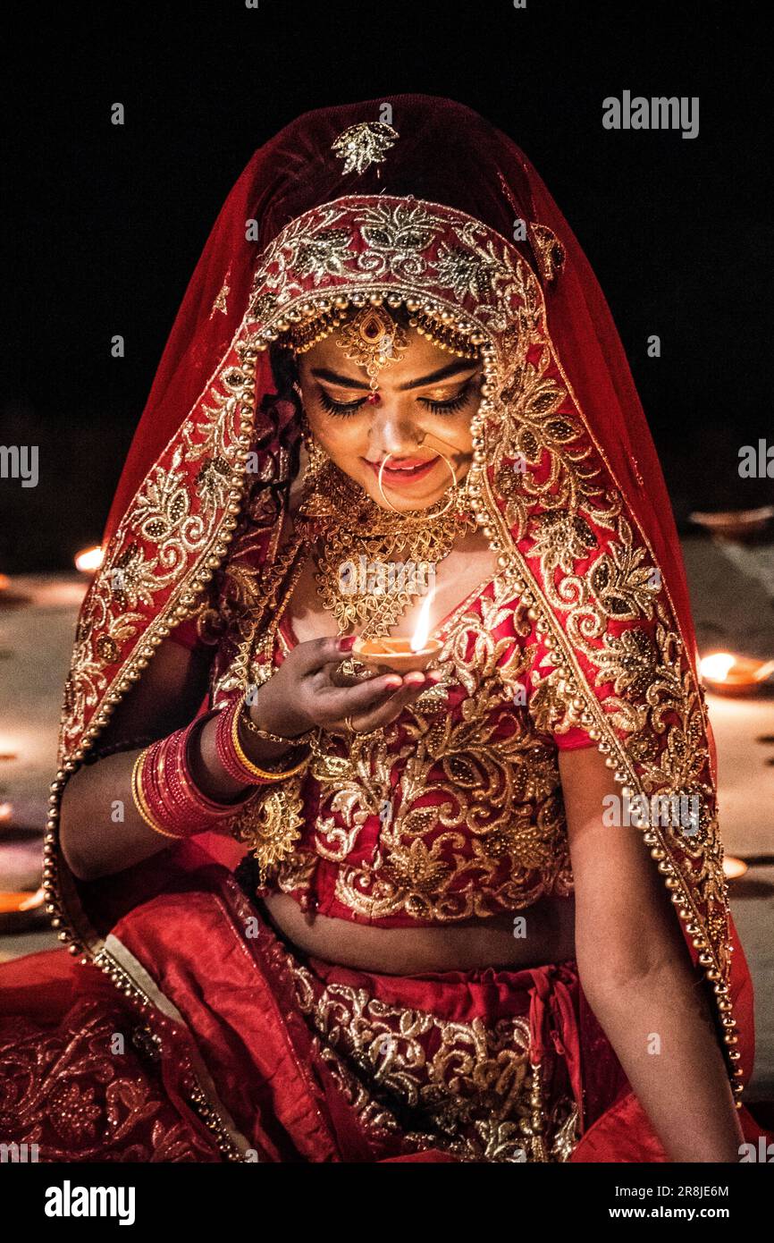 Eine junge Frau in einem Hochzeitssari posiert mit GheeLampen vor DEV