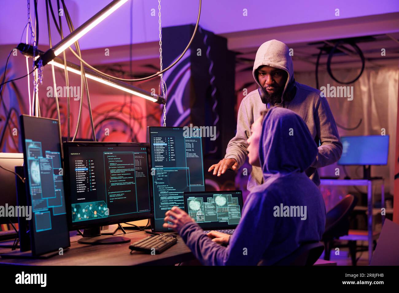 Hacker arbeiten zusammen und kodieren Ransomware auf mehreren Computerbildschirmen. Internetdiebe planen Cyberangriffe, um Informationen vom Datenbankserver im Versteck zu stehlen Stockfoto