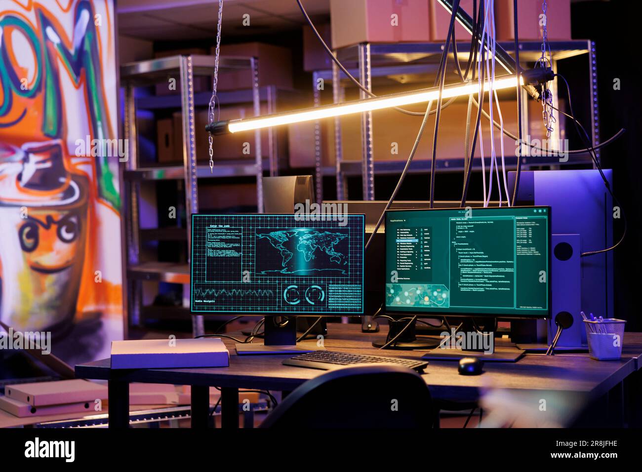 Computerbildschirme zeigen Daten und Ransomware-Code am Hacker-Arbeitsbereich an. Schädliche Software knackt das Passwort auf Monitoren in einem verlassenen Lagerhaus mit Graffiti und Neonlicht Stockfoto