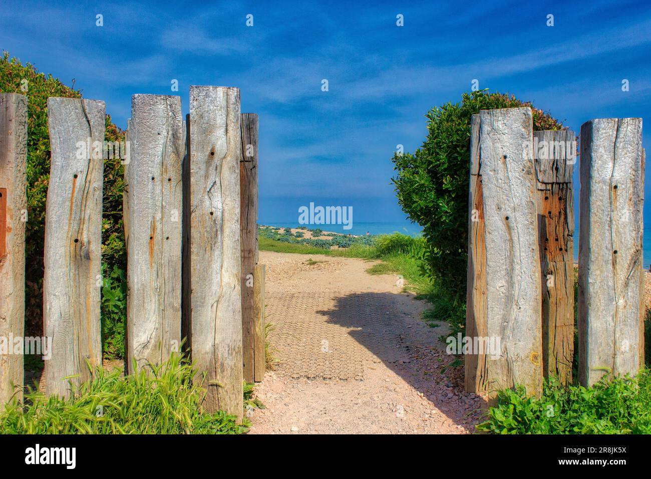 Eine atemberaubende Strandszene mit einem gewundenen Pfad, der von einem kurzen Holztor bewacht wird Stockfoto