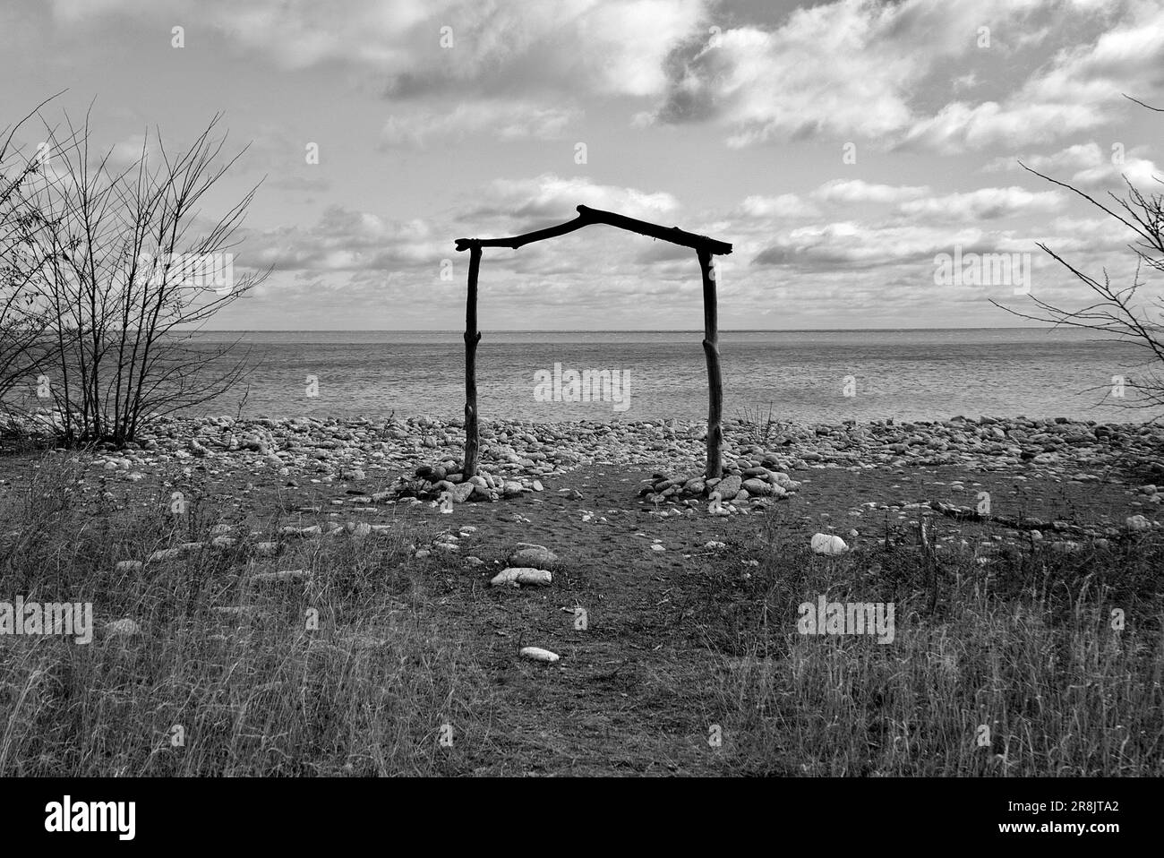 Ein Schwarzweißfoto eines einfachen Holztors am Strand Stockfoto