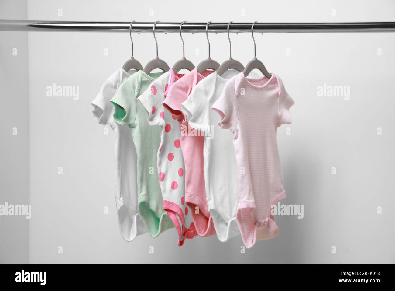 Babykleidung, die an einem Regal in der Nähe der weißen Wand hängt Stockfoto