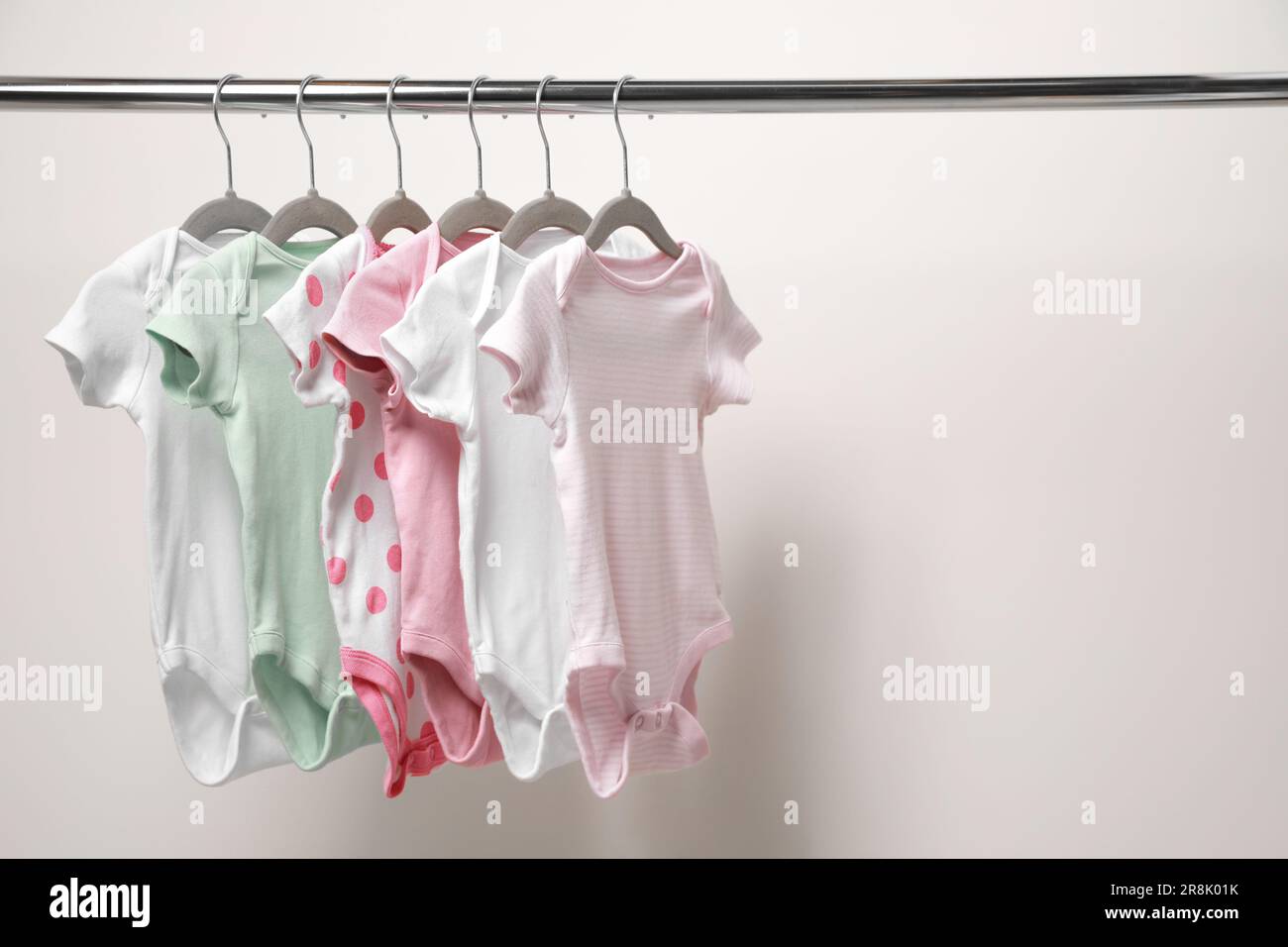 Babykleidung, die an einem Regal in der Nähe der weißen Wand hängt. Platz für Text Stockfoto