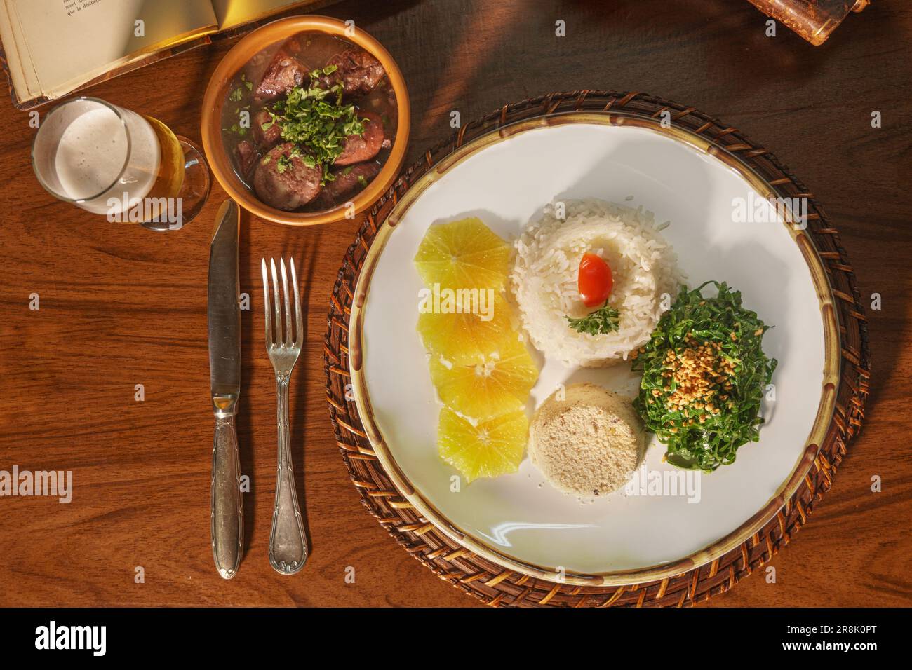 Wunderschönes Gericht mit Feijoada und Bier. Im Hintergrund alte Bücher Stockfoto
