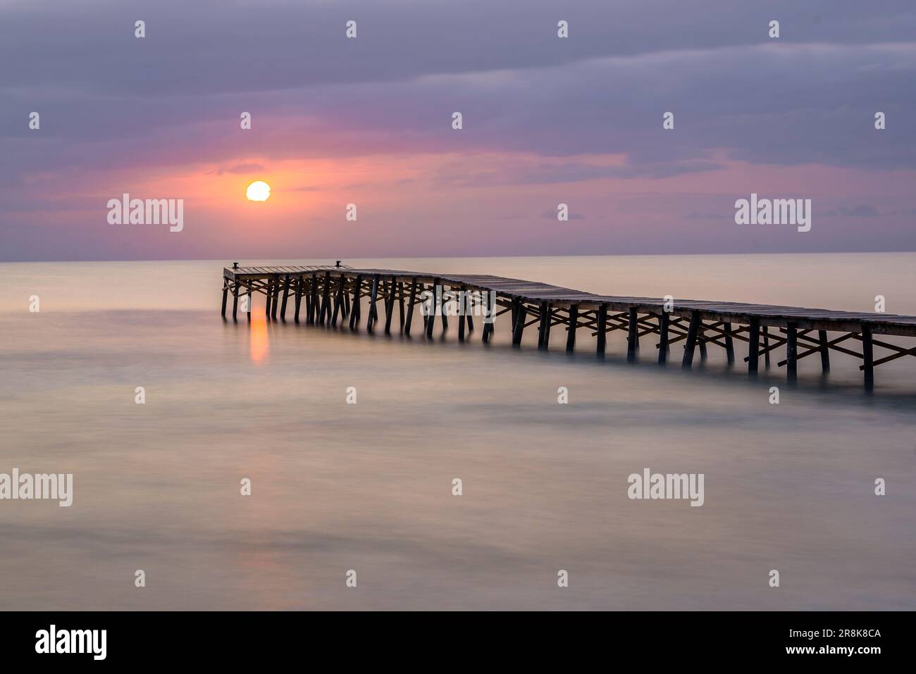 Sommersonnenaufgang auf einem hölzernen Pier an einem Strand in Platja de Muro (Mallorca, Balearen, Spanien) ESP: Amanecer veraniego en un muelle de madera en Muro Stockfoto